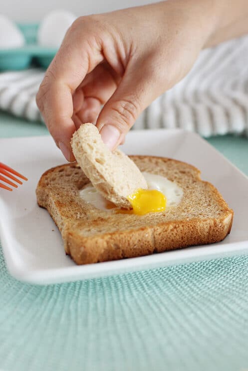 Someone dipping bread into an egg yolk