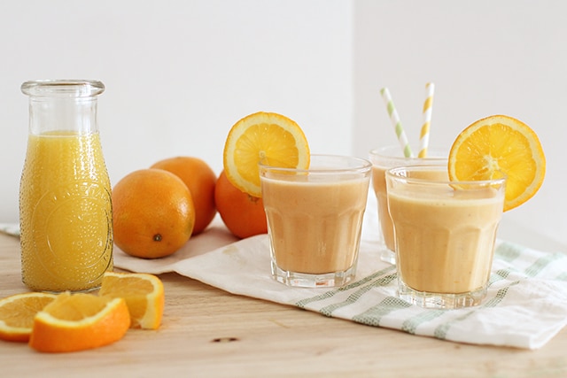 homemade orange julius in glass with fresh oranges