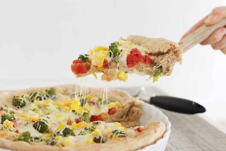 Deep dish veggie pizza slice with stretchy cheese