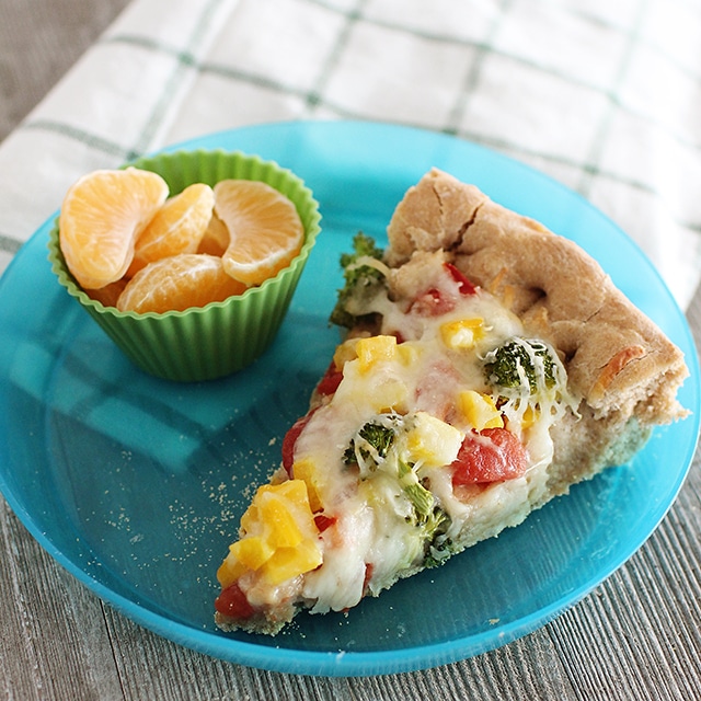 Re-invent Friday night family dinner with Deep Dish Veggie Pizza! This pizza is made with homemade, whole wheat dough and topped with fresh veggies for tons of flavor and nutrition. veggie pizza on kids plate with oranges