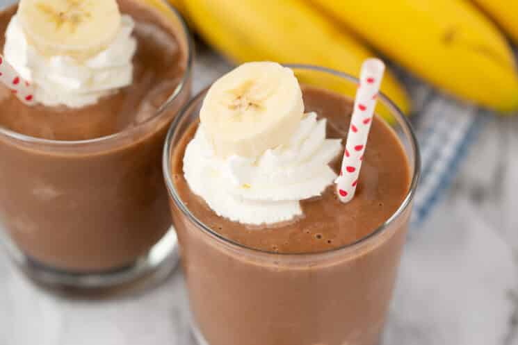 creamy chocolate smoothie with bananas and whipped cream and a straw