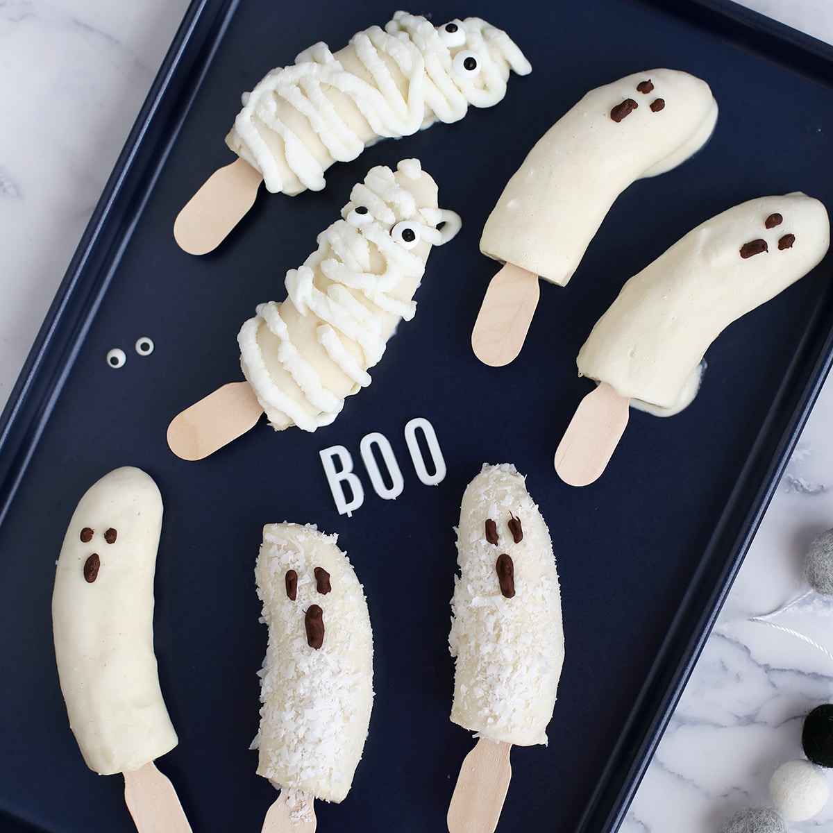 halloween banana pops on a dark baking sheet