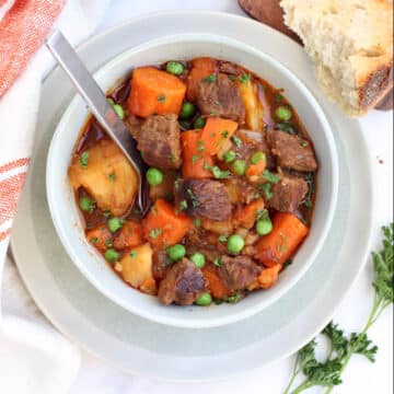 overhead view of a bowl of beef stew with a spoon in the bowl