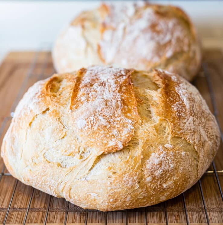 Two loaves of rustic round loaves of artisan bread on cooling racks