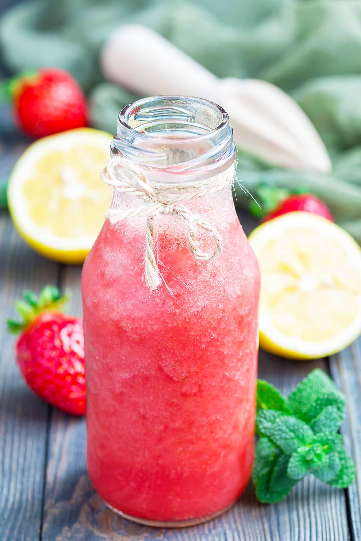 Homemade strawberry lemonade with fresh strawberry, lemon, ice and mint in glass bottle, vertical