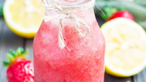 Homemade strawberry lemonade with fresh strawberry, lemon, ice and mint in glass bottle, vertical