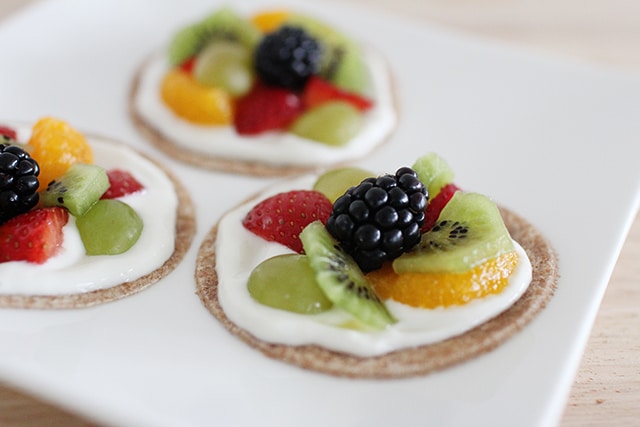 Not your traditional sugar-laden cookie! This healthy fruit pizza recipe takes ten (no-cook!) minutes to make and features wholesome ingredients you can feel good about serving. close up of fruit pizzas