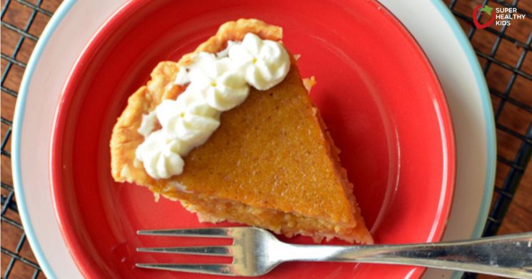 butternut squash pie topped with whipped cream on a red plate