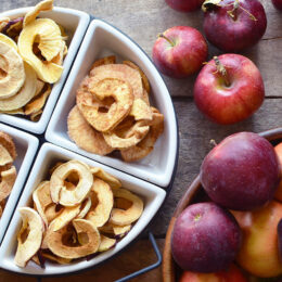 Cinnamon Sugar Dried apples in a white dish with red apples in the background