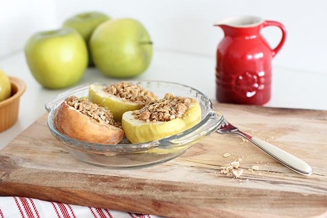 Warm baked apples are easy for little ones to chew and stuffed with an irresistible streusel topping made from whole grain oats, brown sugar, and spices. baked apples in a dish on a cutting board