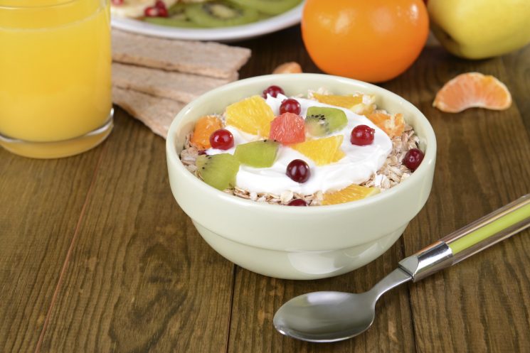 Delicious oatmeal with fruit in bowl on table close-up