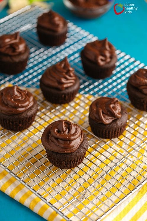 gluten free mini chocolate cupcakes with chocolate frosting on cooling rack