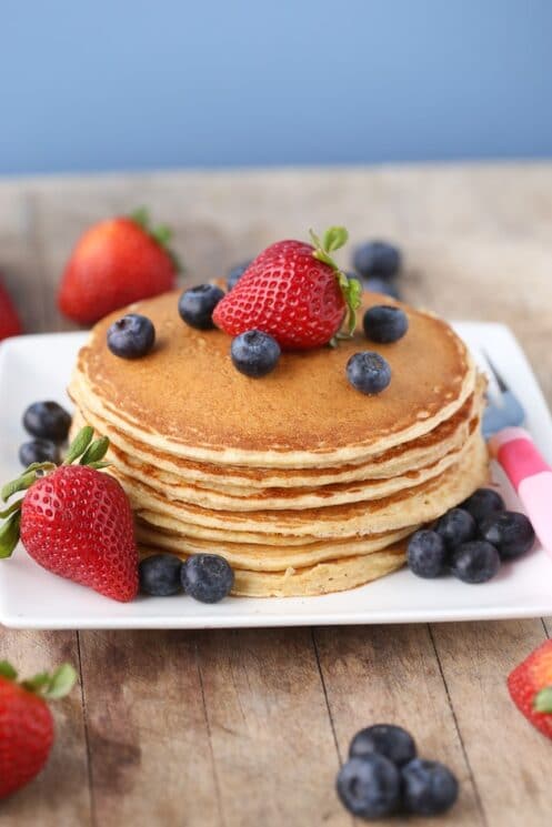Cottage Cheese Protein Pancakes stacked on a plate with strawberries and blueberries