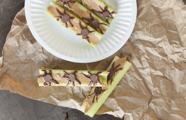 celery sticks topped with peanut butter with chocolate chip spiders for decoration