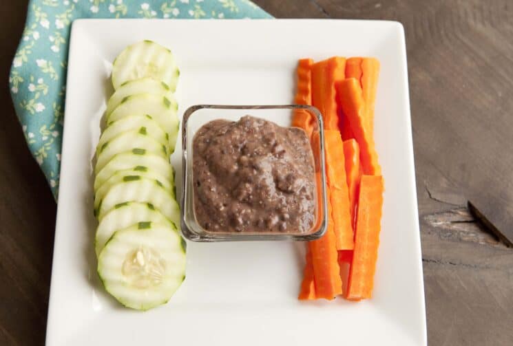 Popcorn with pumpkin seeds and dried cranberries in a wooden bowl.

Bean dip served with sliced cucumbers and carrots.