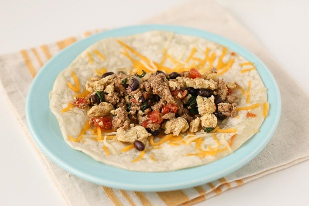 tortilla topped with cheese, beans, and ground turkey on a blue plate