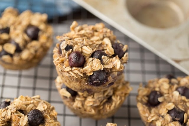 oatmeal blueberry muffins stacked on a cooling rack