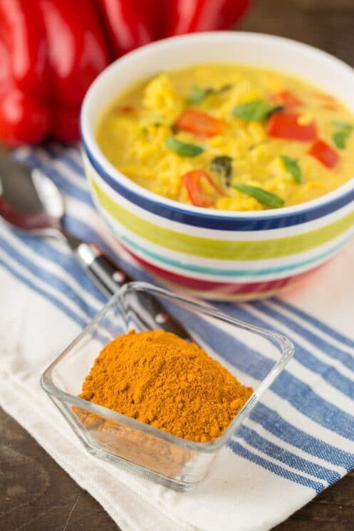 a bowl of chicken and rice soup next to a dish of turmeric