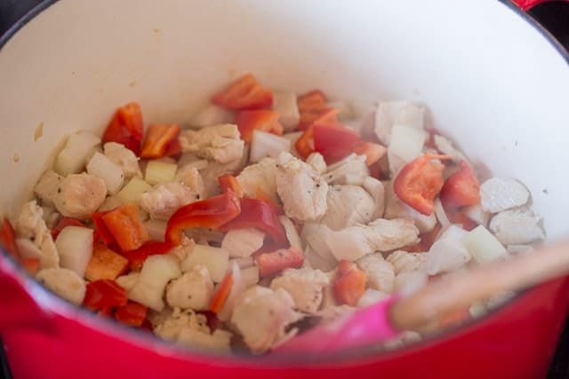 chicken, bell peppers and onions cooking in a large pot