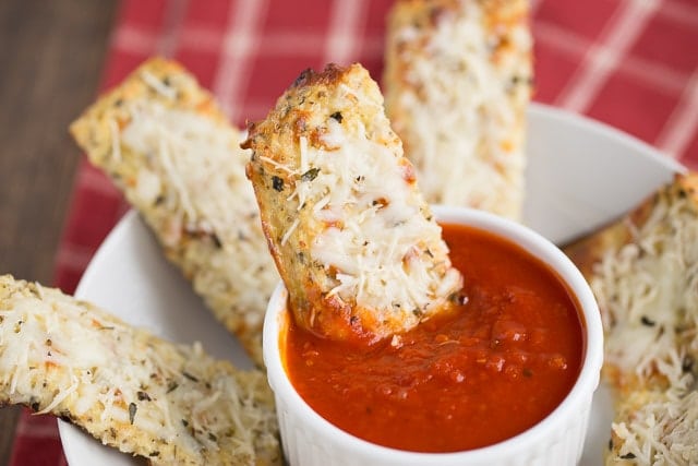 Healthy Cheesy Cauliflower Breadsticks being dipped in marinara sauce