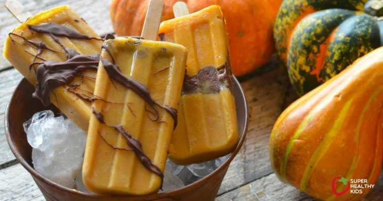 orange and chocolate popsicles in a bowl of ice with squash in the background