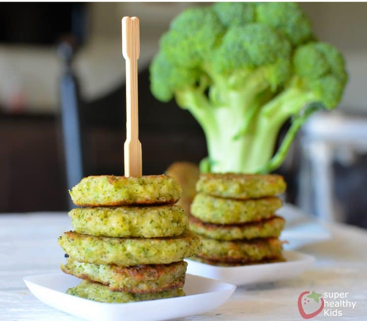 small stacks of cheesy broccoli fritters on small serving plates with a serving pick on top