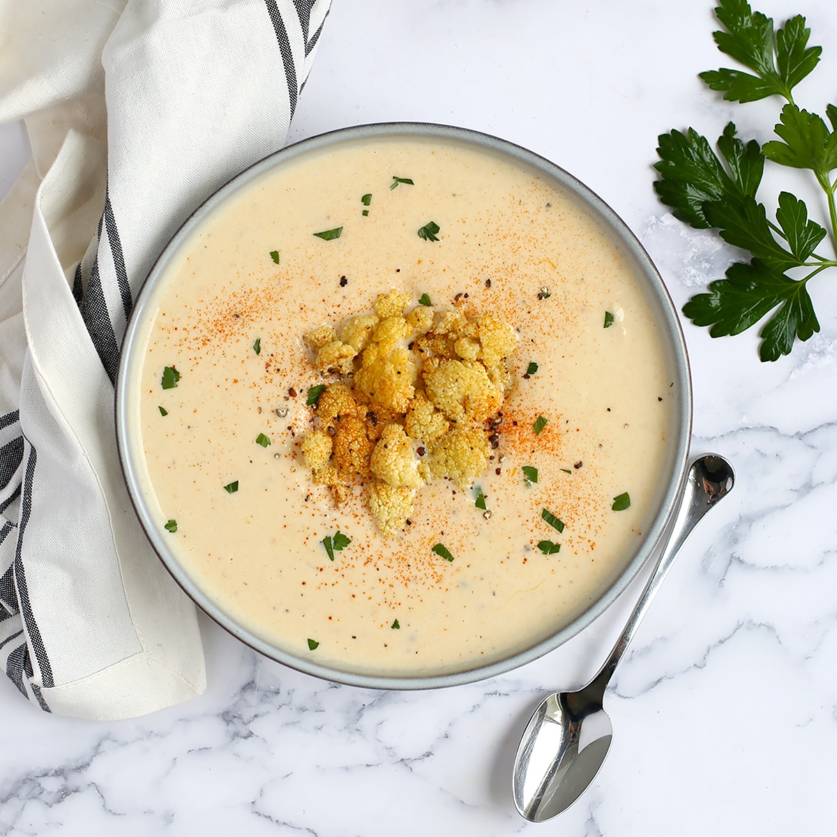 creamy cauliflower soup in a bowl with roasted cauliflower on top as a garnish