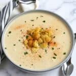 creamy cauliflower soup in a bowl with roasted cauliflower on top as a garnish