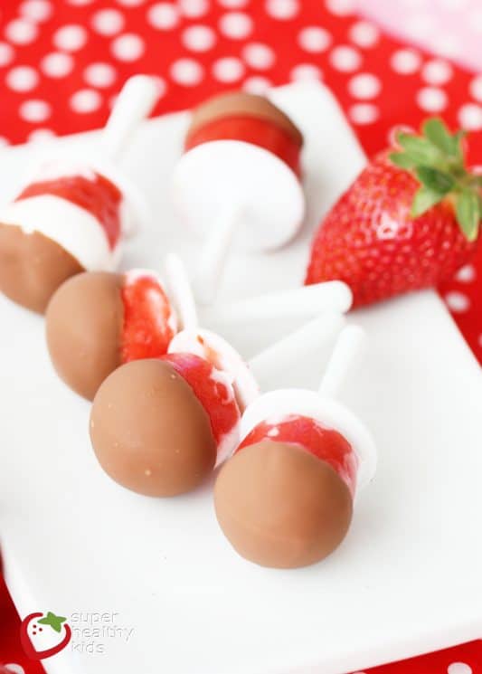 chocolate covered strawberry popsicles on a white serving plate