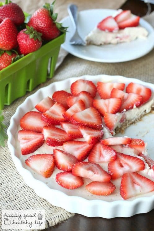 Strawberry Tart in a white pan in front of a container of fresh strawberries
