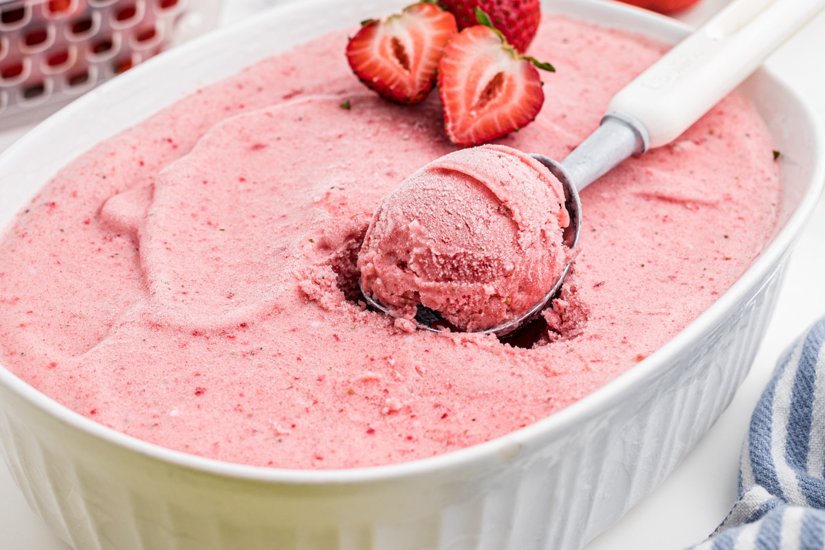 strawberry banana frozen yogurt in a white glass dish with an ice cream scoop