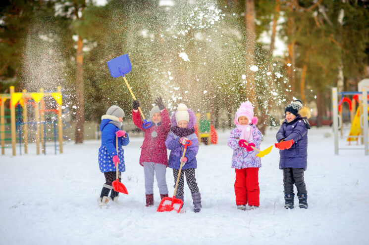 a group of kids playing in the park in the snow