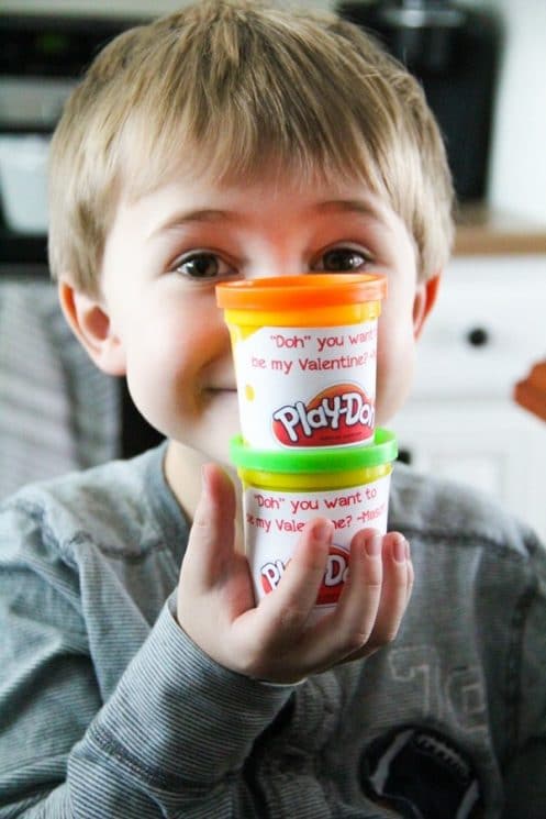 a young boy holding play doh with a valentines message on it