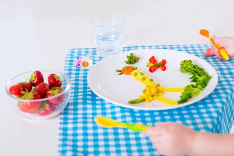 Top 20 Finger Foods For Baby - Healthy vegetarian lunch for little kids. Kid meal. Vegetable and fruit served as animals, corn, broccoli, carrot, strawberry helping child to learn eating right and clean, children hands with spoon