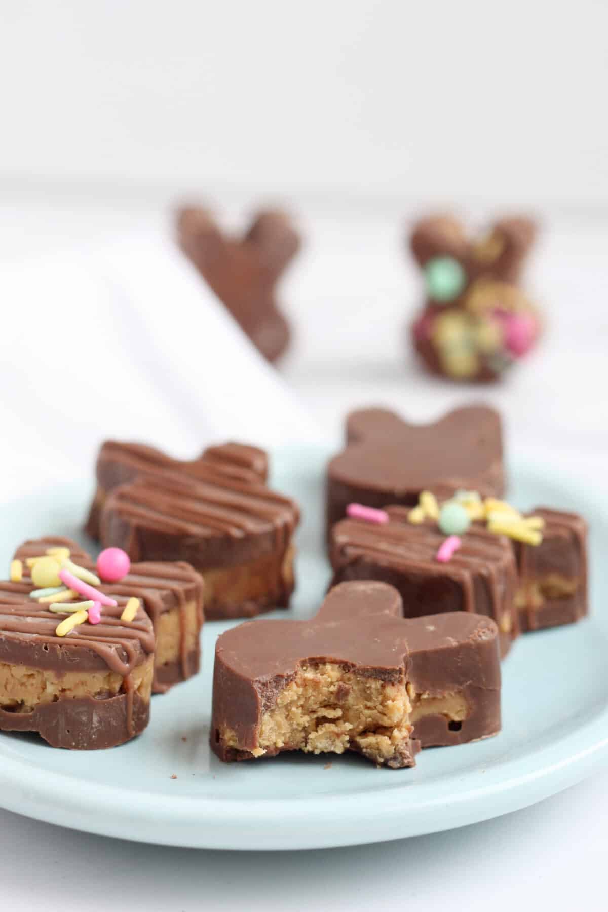 peanut butter cup bunnies on a blue plate with a bite of one of the bunnies
