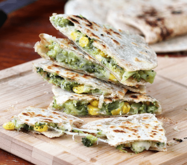 broccoli and cheese quesadillas stacked on a wooden cutting board