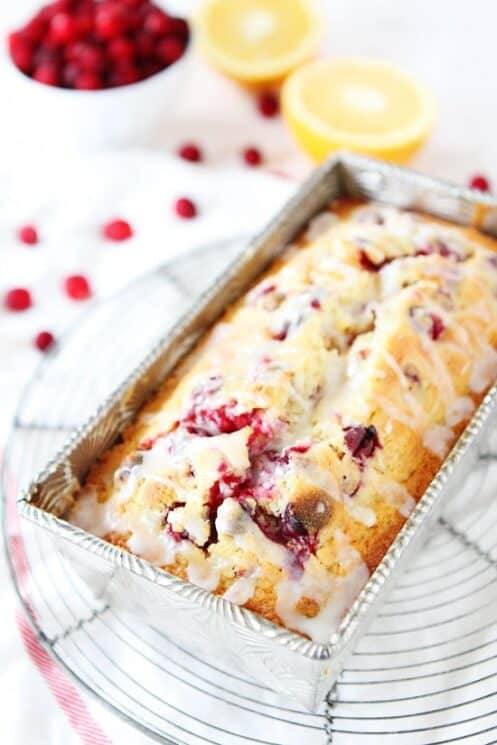 orange cranberry bread drizzled with glaze in a pan