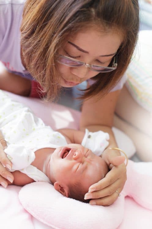 women and infant crying on the baby bed