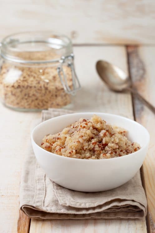 white bowl of cooked quinoa on a kitchen towel