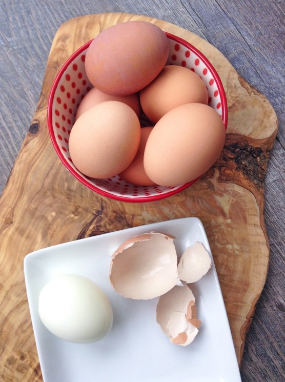 hard boiled eggs in a bowl on a wooden tray