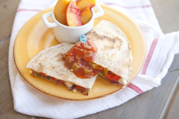 grilled quesadillas topped with salsa and served with peaches on a yellow plate