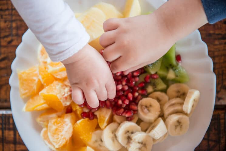 Healthy Snacking for Toddlers - Fruit and Veggie Healthy Snacks for Toddlers, toddlers grabbing cut up fruits from a bowl