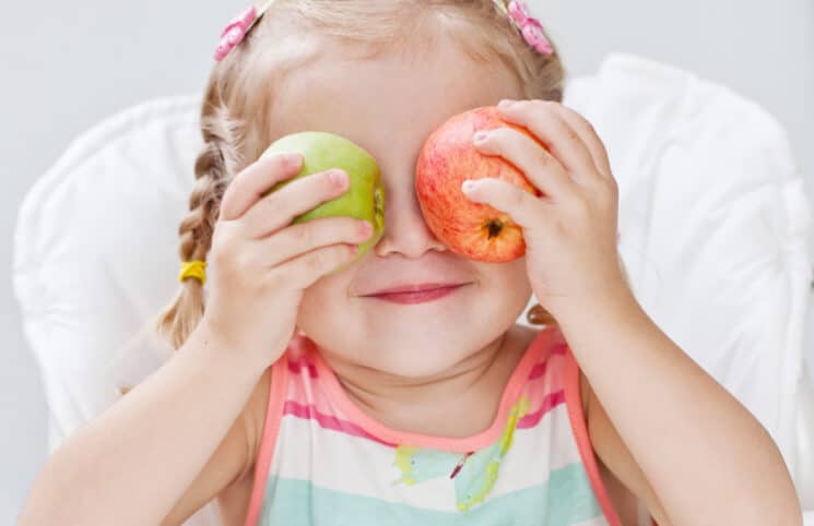 Healthy Snacks for Toddlers, toddler with apples over her eyes