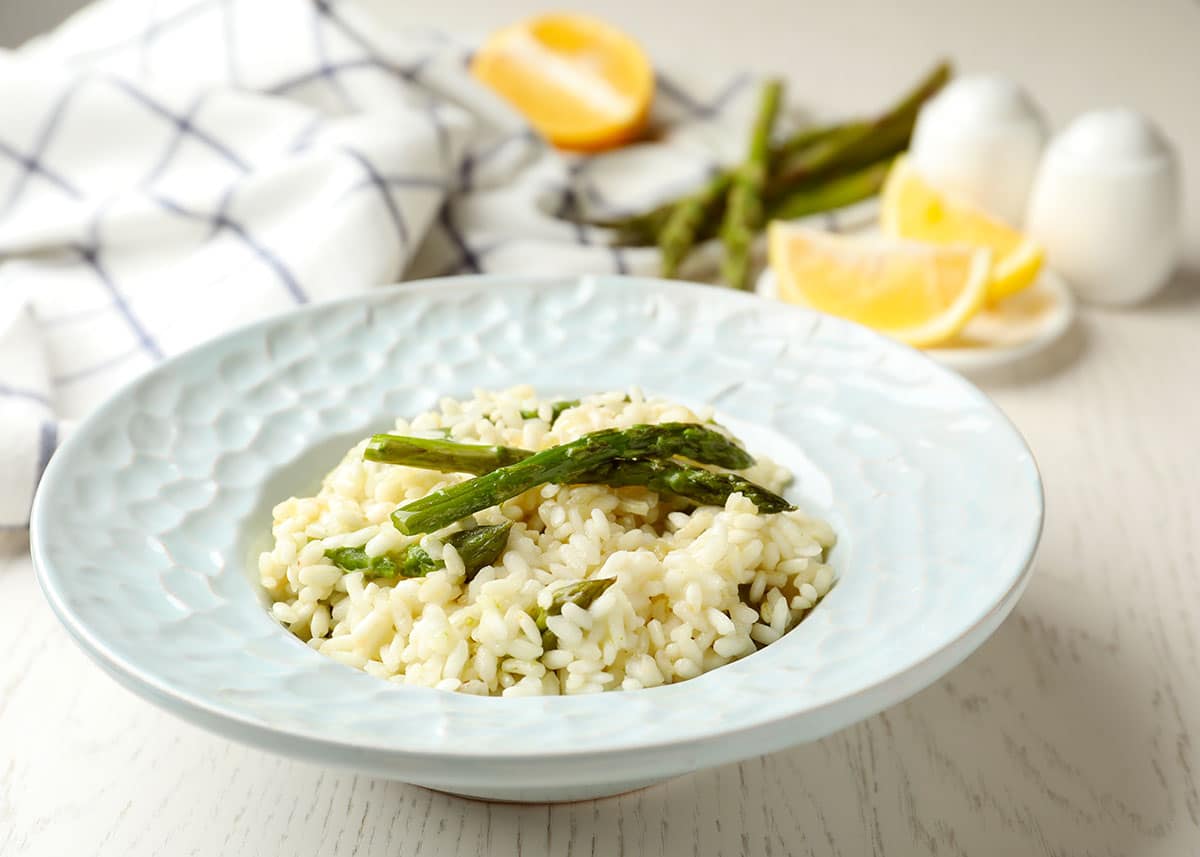 Delicious risotto with asparagus on white wooden table