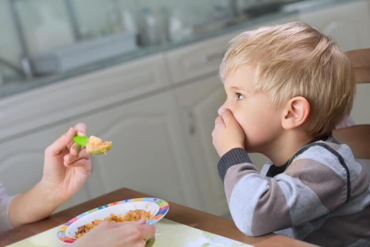boy with hand over his mouth doesn't want to eat the dinner his mom cooked