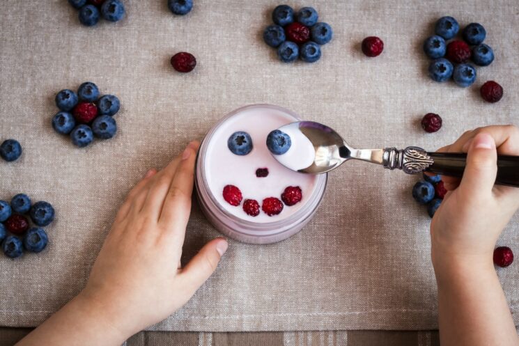 Natural Probiotics for kids through yogurt. Kids hands with berries and yogurt.