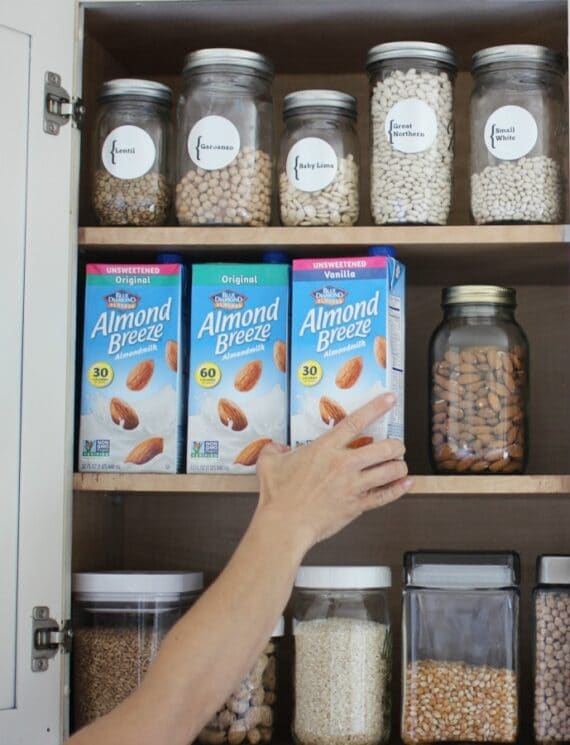 Reaching for shelf stable almond milk in a cupboard