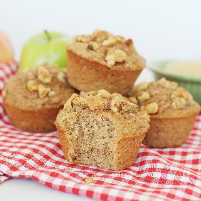 stack of delicious 100% whole wheat applesauce muffins for kids with a bite taken out of one of the muffins