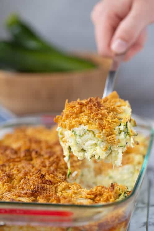 scooping zucchini casserole out of baking dish