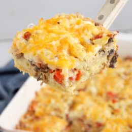 breakfast casserole slice close up on a spatula with the breafkast casserole in the baking dish in the background